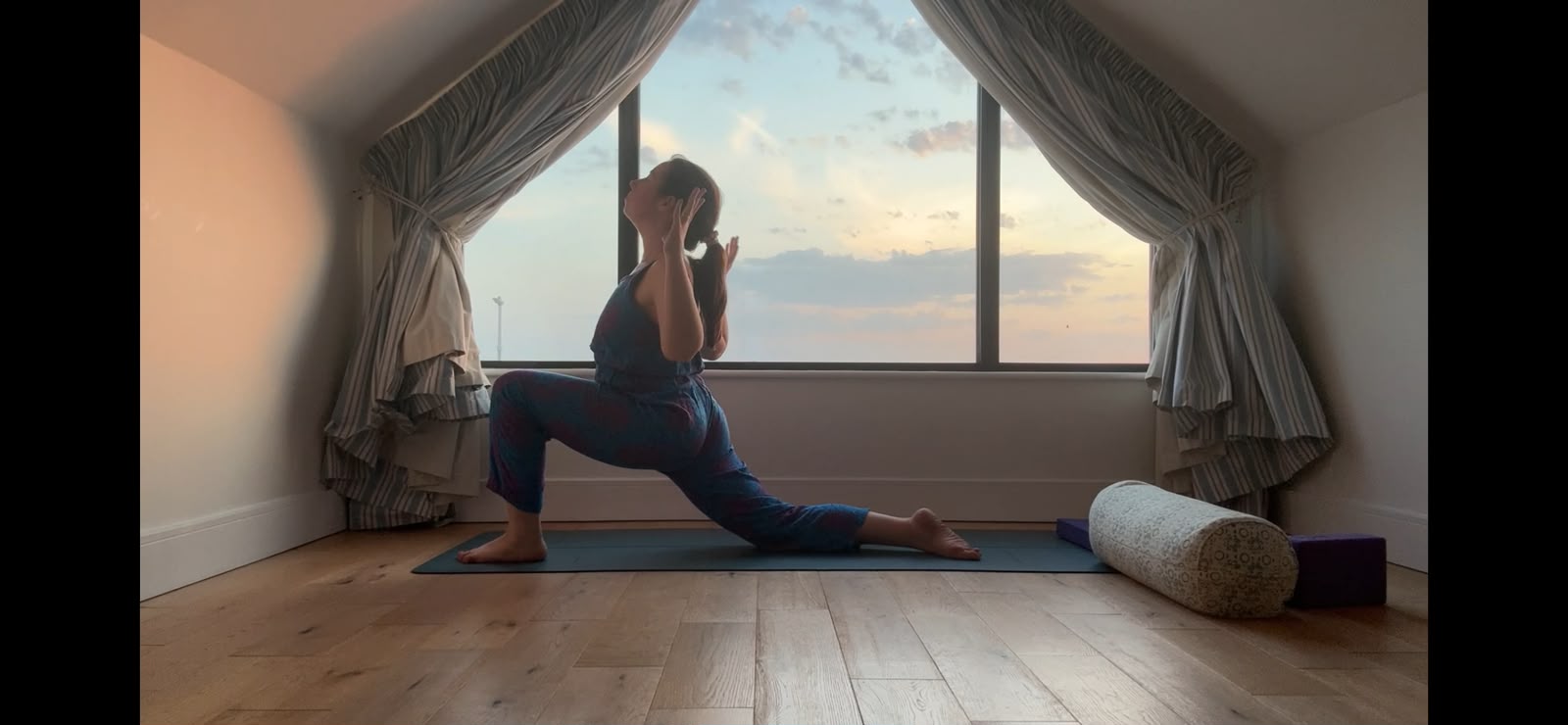 Serena Kenny practicing heart-opening yoga pose by the window